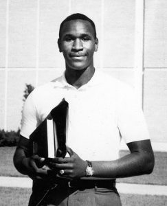Ernest Boger, a male student in his early 20s, holding several books as he walks on the USF campus.