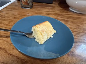 A slice of Wisconsin Crumb Cake on a blue plate with a fork, showing its soft and airy interior beneath the crumb topping.