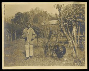 Lue Gim Gong holding an orange and his favorite pet rooster he named "March".