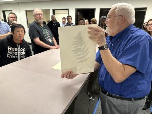 USF Libraries Dean Todd Chavez holding up a USF Herbarium specimen to show USF Libraries employees.