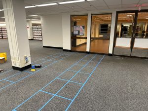 An empty space in the USF Libraries basement is outlined with blue painters tape in the shape of squares to mark the location of where the USF Herbarium specimens will eventually be held.