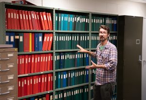 Man stands in front of shelf of books in research facility