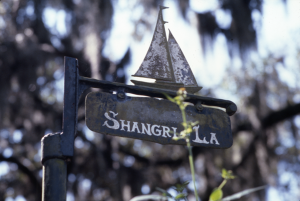 An iron sign says "Shangri-La" with a cutout of a sailboat at the top.