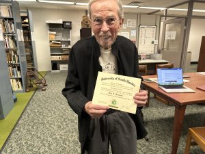A man holding up his Bachelor of Arts diploma from USF.